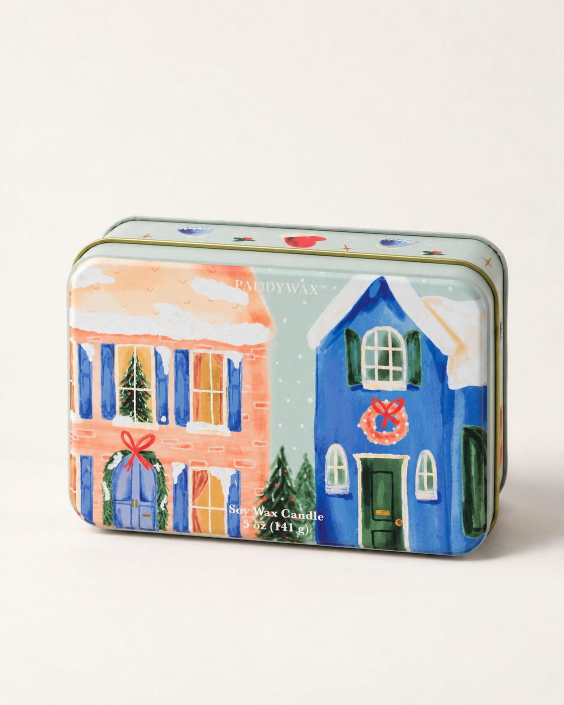 1. Detalle de lata PADDYWAX con casas nevadas, ventanas iluminadas y coronas navideñas.