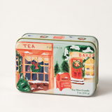 Detalle de lata navideña PADDYWAX con tienda de té, panadería, coronas y buzón de Papá Noel.