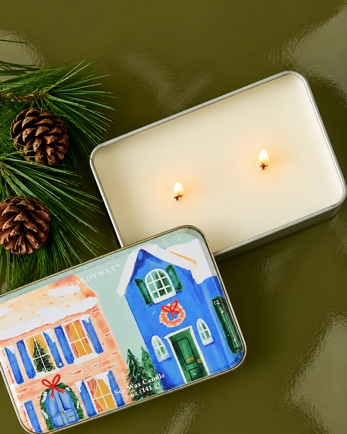 Vela navideña PADDYWAX abierta con dos mechas y cera de soja en lata decorativa.